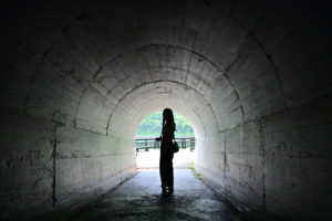 岩手・浄土ヶ浜、海へ抜けるトンネルの中で振り向く女性、先に広がる青さを感じる情景（撮影:Nikon Z6III）